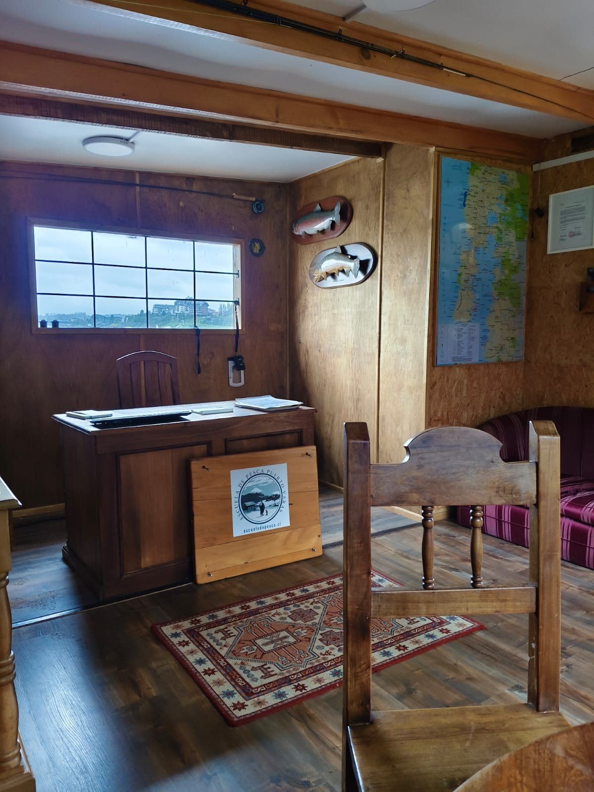 Escritorio de atención con el logo de la Escuela de Pesca Puerto Varas y vista al lago