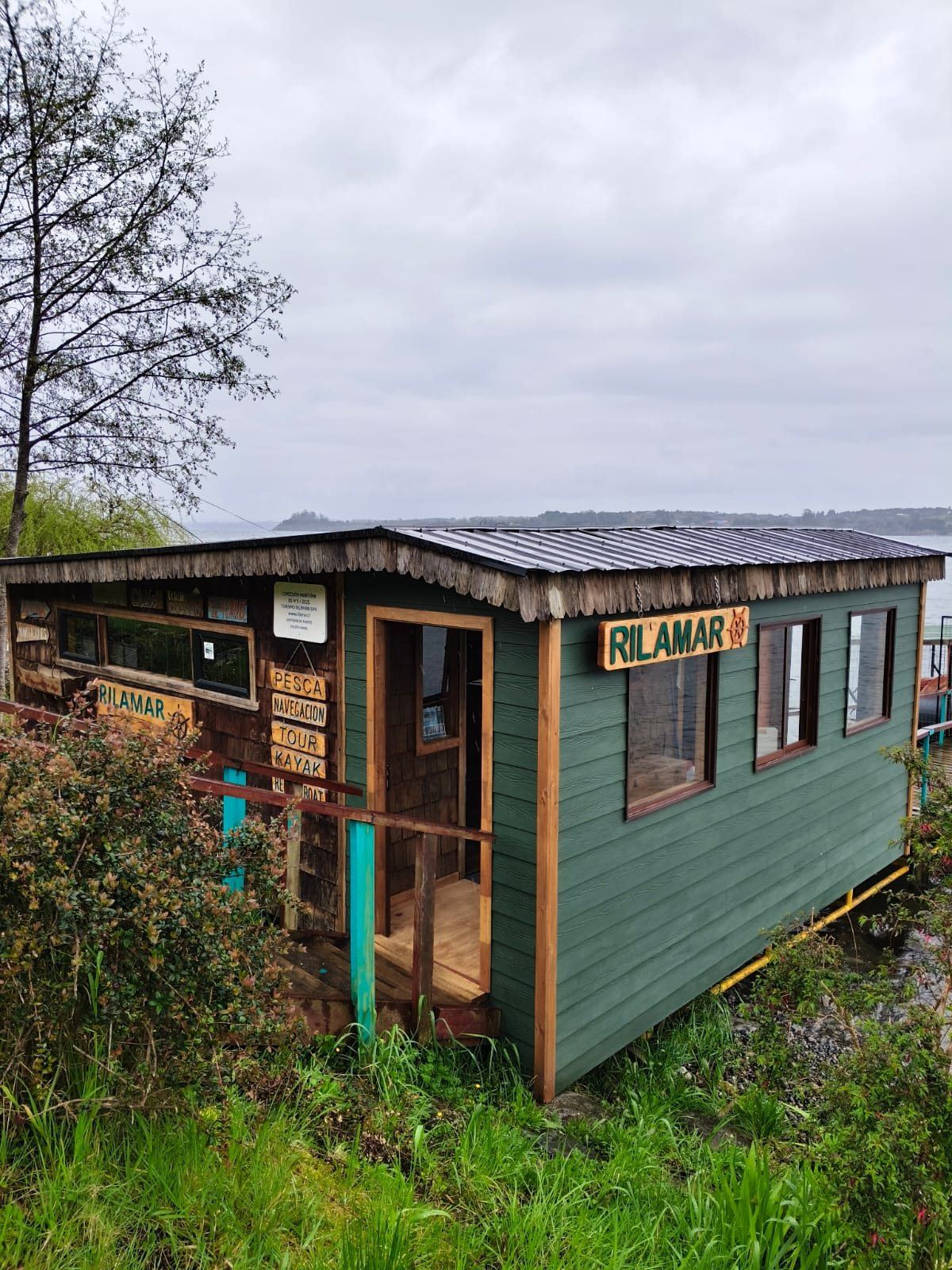 Oficina Rilamar renovada, de madera verde con letrero tallado, a orillas del Lago Llanquihue